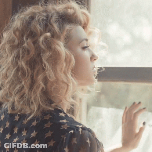 Woman With Curly Blonde Hair Looking Out Window GIF