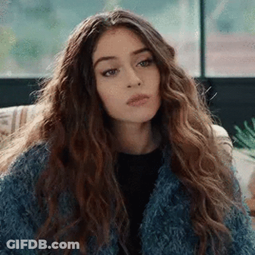 Woman With Curly Hair And Blue Fur Coat On Couch GIF