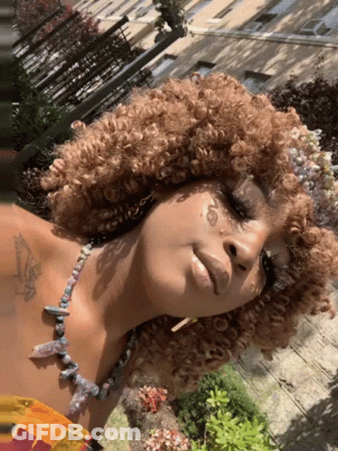 Woman With Curly Hair And Chest Tattoo GIF