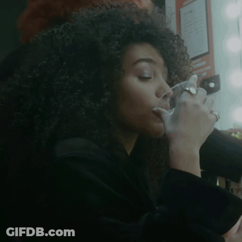 Woman With Curly Hair Drinking From Glass GIF