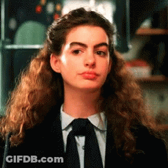 Woman With Curly Hair In Black Suit And Tie GIF