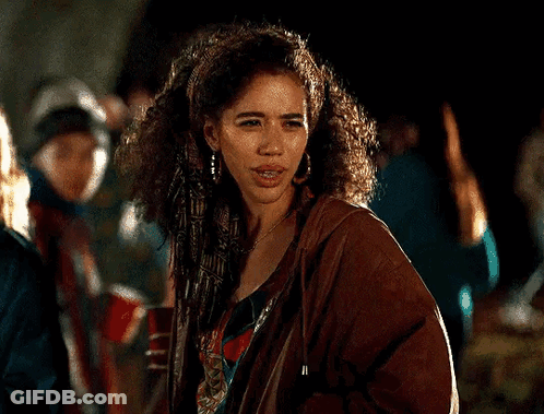 Woman With Curly Hair In Brown Jacket And Earrings In Crowd GIF