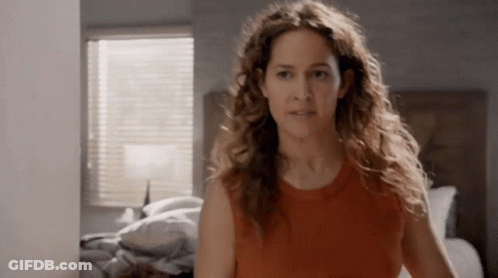 Woman With Curly Hair In Front Of Bed GIF