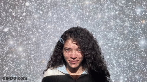 Woman With Curly Hair In Snowy Sky GIF