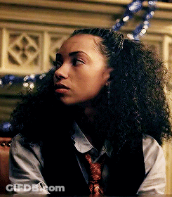 Woman With Curly Hair In Vest And Tie Sitting At Table GIF