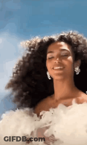 Woman With Curly Hair In White Dress Smiling Eyes Closed GIF