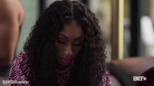 Woman With Curly Hair In Zebra Print Shirt On Couch GIF