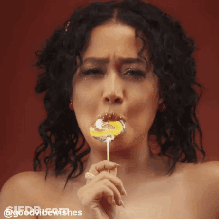 Woman With Curly Hair Licking Swirl Lollipop GIF