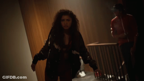 Woman With Curly Hair Looking At Camera In Dark Room GIF