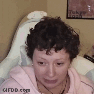 Woman With Curly Hair Sitting In Chair Making Face GIF