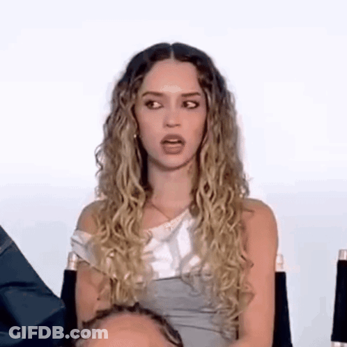 Woman With Curly Hair Sitting In Chair Making Funny Face GIF