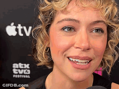 Woman With Curly Hair Smiling In Front Of Apple TV Sign GIF