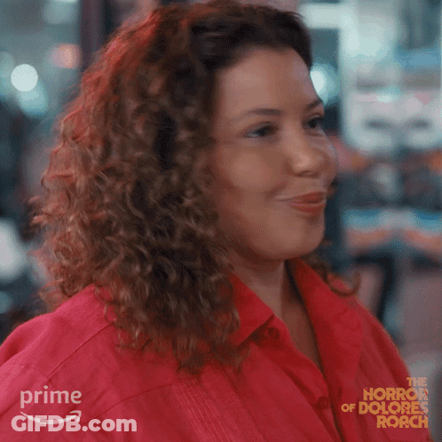 Woman With Curly Hair Smiling In Red Shirt From The Horror Of Dolores Roach GIF