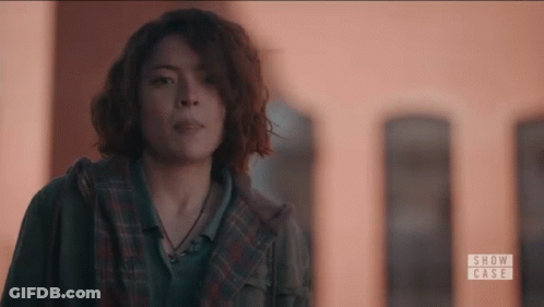 Woman With Curly Hair Standing In Front Of Building GIF