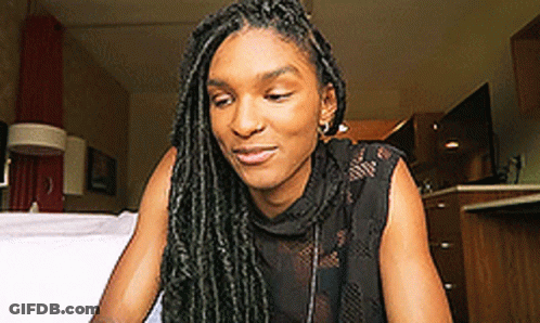 Woman With Dreadlocks Sitting On Bed Looking Down GIF