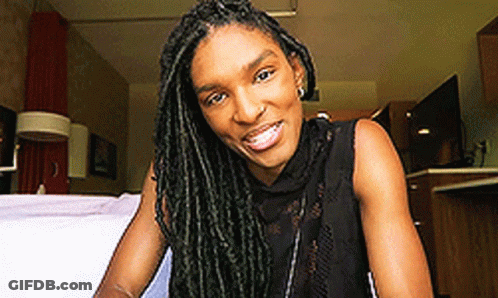 Woman With Dreadlocks Sitting On Bed Smiling GIF