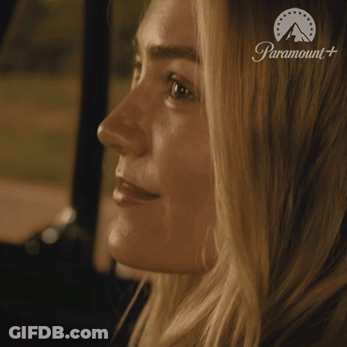 Woman With Eyes Closed Saying Show Me In Front Of Paramount Sign GIF