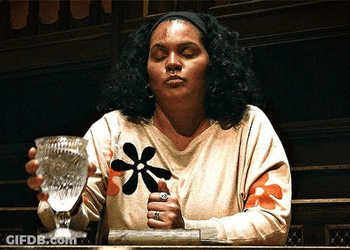 Woman With Flower On Sweater Holding Glass GIF