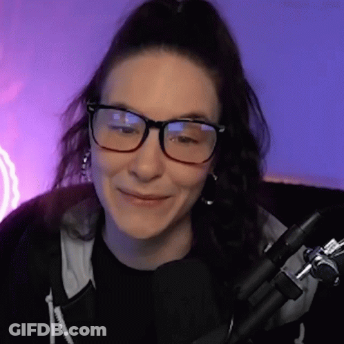 Woman With Glasses And Black Shirt Smiling In Front Of Microphone GIF