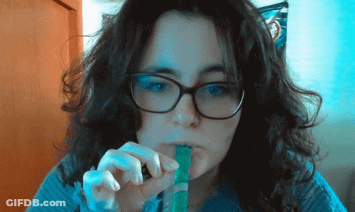 Woman With Glasses And Blue Sweater Eating Green Stick GIF