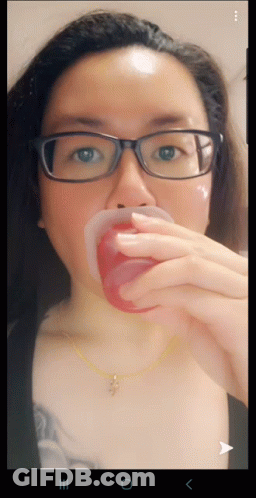 Woman With Glasses And Cross Necklace Holding Red Cup In Mouth GIF