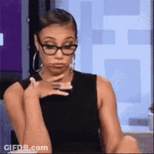 Woman With Glasses And Earrings Sitting At Table GIF