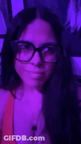 Woman With Glasses And Necklace Taking Selfie In Purple Room GIF