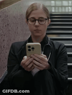 Woman With Glasses And Stethoscope Sitting On Stairs Looking At Cell Phone GIF