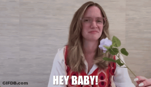 Woman With Glasses Holding Flower Saying Hey Baby GIF