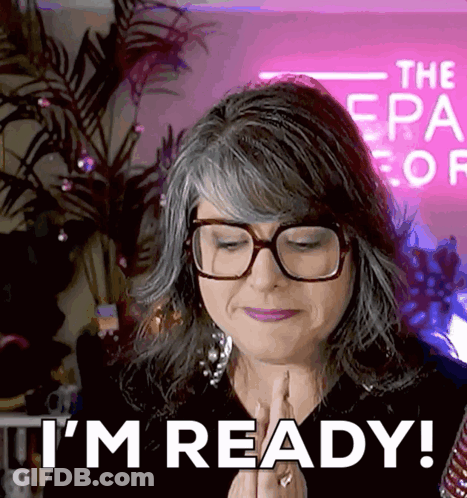 Woman With Glasses Says I'm Ready In Front Of Pink Sign GIF