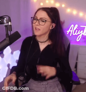 Woman With Glasses Sitting At Microphone In Front Of Aliyja Sign GIF