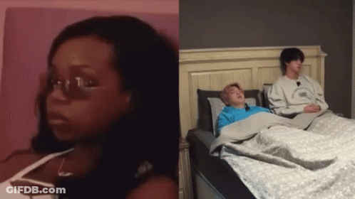 Woman With Glasses Sitting Next To Man In Bed GIF
