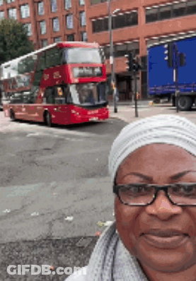 Woman With Glasses Taking Selfie In Front Of Double Decker Bus GIF