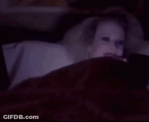 Woman With Glowing Eyes Smiling In Bed GIF