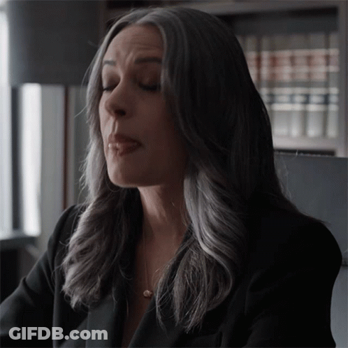 Woman With Gray Hair Sitting In Front Of Bookcase GIF
