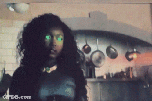 Woman With Green Eyes In Kitchen With Hanging Pots And Pans GIF