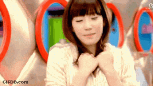 Woman With Hands On Chest In Front Of Wall With Circles GIF