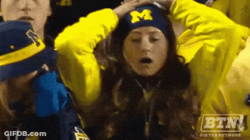 Woman With Hat With Letter M In Crowd GIF