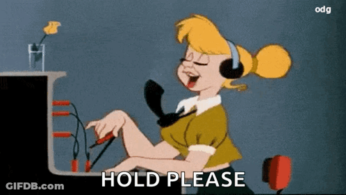 Woman With Headphones At Desk Saying Hold Please GIF
