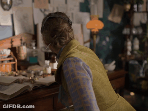 Woman With Headphones At Desk With Lamp GIF