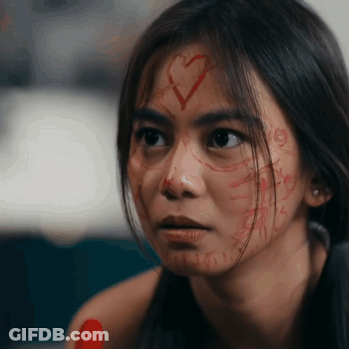 Woman With Heart Drawn On Face Looks At Camera GIF
