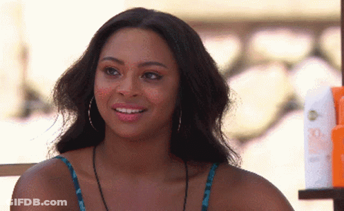 Woman With Hoop Earrings Smiling Next To Sunscreen Bottles GIF