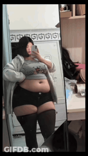 Woman With Large Belly In Front Of Mirror GIF