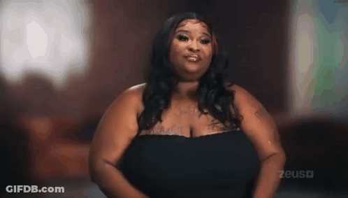 Woman With Large Breasts In Black Dress Looking At Camera GIF