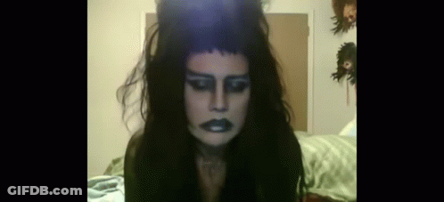 Woman With Long Black Hair And Crown Sitting On Bed GIF
