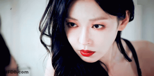 Woman With Long Black Hair And Red Lips Looking In Mirror GIF