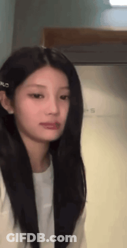 Woman With Long Black Hair And White Shirt Standing In Front Of Door GIF
