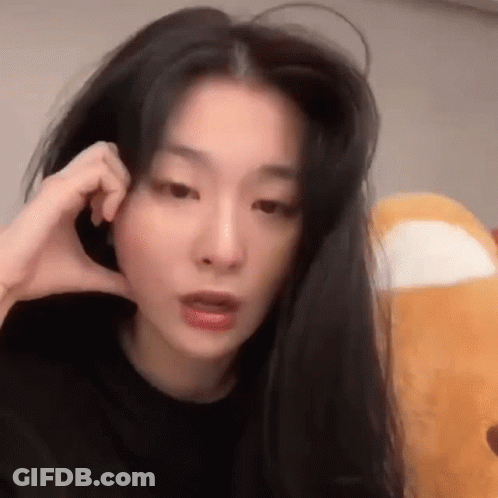 Woman With Long Black Hair Making Phone Call Holding Stuffed Animal GIF