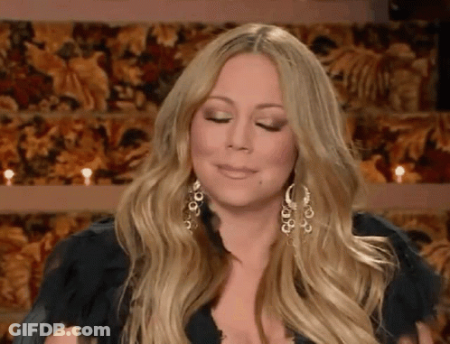 Woman With Long Blonde Hair And Earrings Sitting By Candles GIF