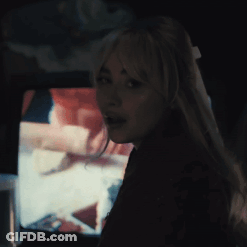 Woman With Long Blonde Hair Looking At Camera In Dark Room GIF
